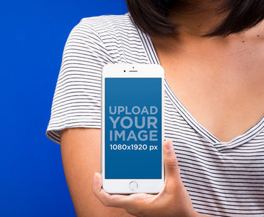 Mockup of a Silver iPhone 8 Held by a Woman Wearing a Striped Shirt