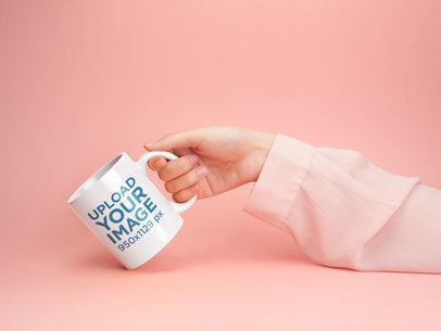Mockup of a Woman's Hand Holding a Coffee Mug Against a Pale Pink Background 22371
