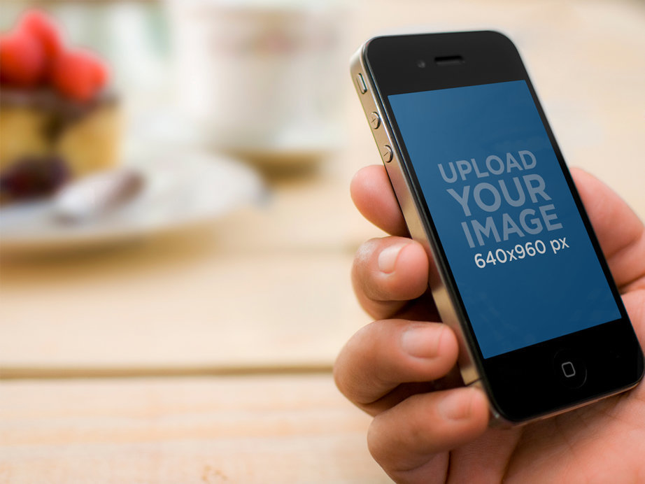 Mockup of a Man Having Breakfast While Looking at a Black iPhone 4