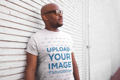 T Shirt Mockup of a Middle-Aged Man with Sunglasses Against a White Textured Wall