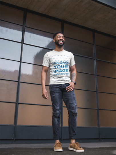 T-Shirt Mockup of a Stylish Man Smiling in Front of a  Window Wall
