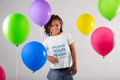 T Shirt Mockup Featuring a Happy Little Girl Between Party Balloons