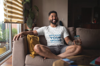 T Shirt Mockup of a Smiling Man with an Arm Tattoo Relaxing at Home