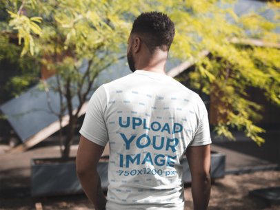 Back View Tshirt Mockup of a Man Facing a House and a Tree