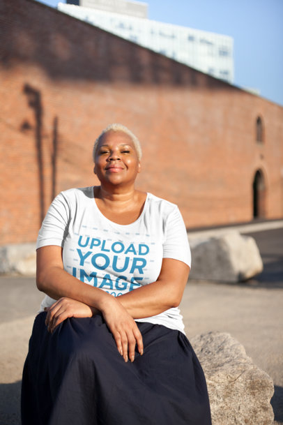 Plus Size T-Shirt Mockup Featuring a Woman Sitting on a Rock