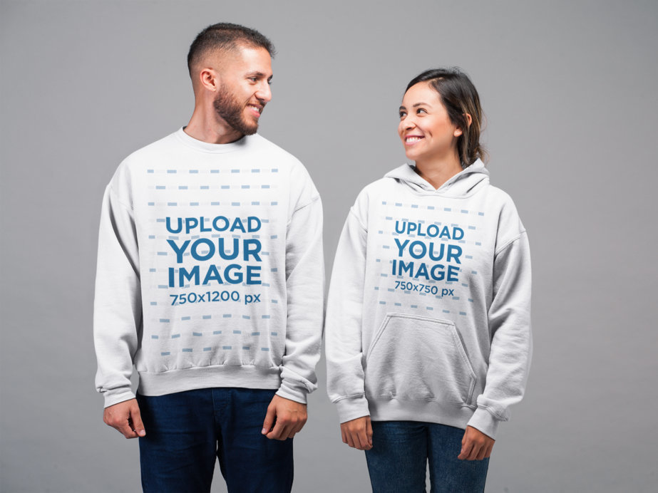 Mockup of a Man Wearing a Sweater and a Woman Wearing a Hoodie Smiling at Each Other in a Studio Setting