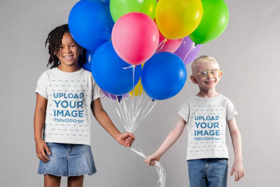Mockup of Two Kids Wearing T-Shirts and Holding Party Balloons Together 22045