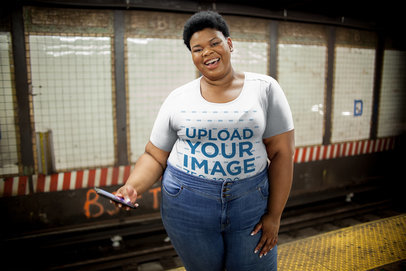 Plus Size T-Shirt Mockup Featuring a Happy Woman with her Phone at a NYC Subway Station