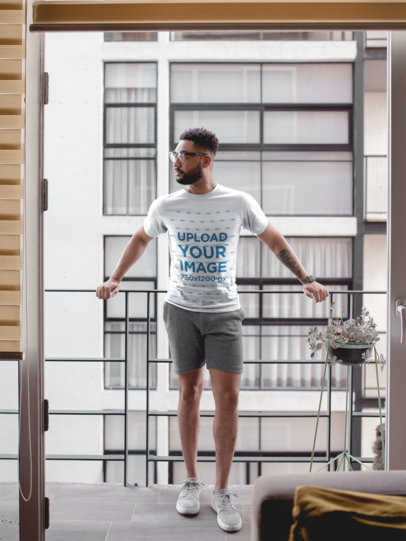 T-Shirt Mockup of a Man Standing on His Balcony