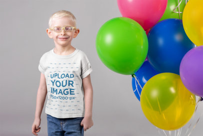 Round Neck Tee Mockup of a Smiling Kid with Glasses Standing Next to a Set of Balloons 22057