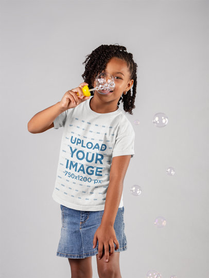 T-Shirt Mockup of a Little Girl Blowing Bubbles in a Studio