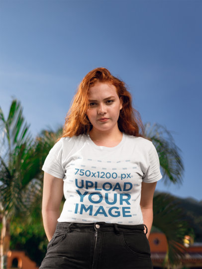 Mockup of a Woman Wearing a T-Shirt with Palm Trees Behind Her