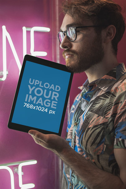 Space Gray iPad Mockup of a Man with Glasses Against a Pink Neon Sign