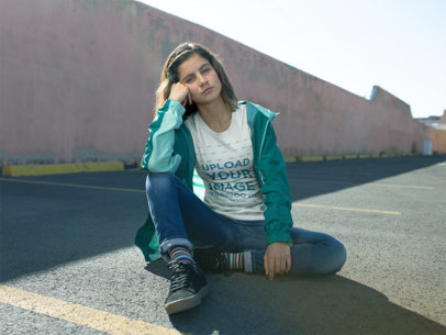 T-Shirt Mockup Featuring a Woman Sitting in an Empty Parking Lot