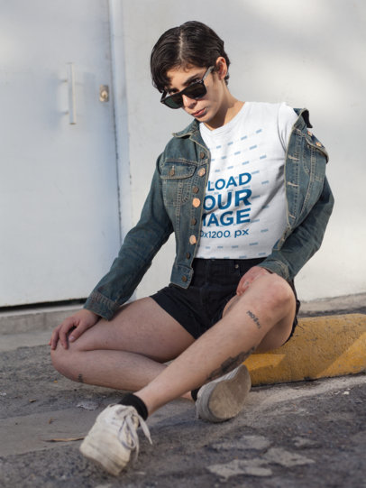 Mockup of a Tattooed Short-Haired Woman Wearing a T-Shirt Sitting at a Parking Lot