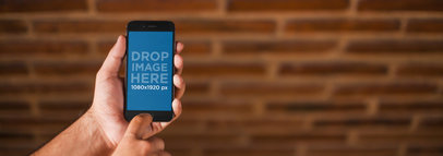 iPhone 6 Mockup of a Man Holding his iPhone in Front of a Brick Wall