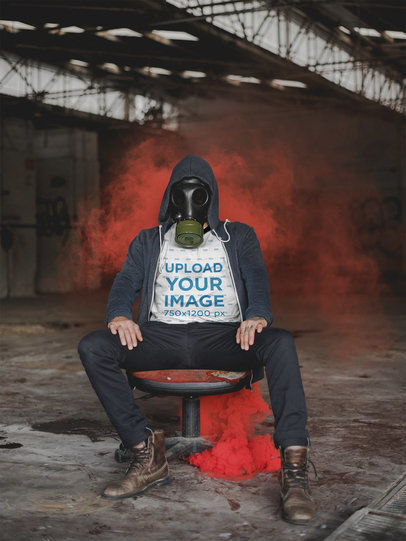 T-Shirt Mockup of a Man with a Gas Mask Sitting Near Red Smoke