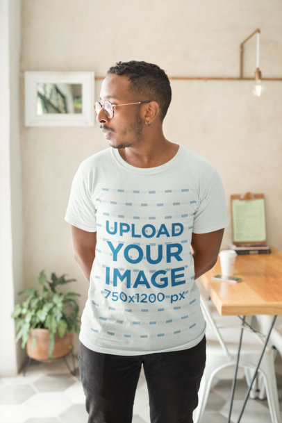 Mockup of a Man Wearing a T-Shirt in His Apartment Looking Towards His Window