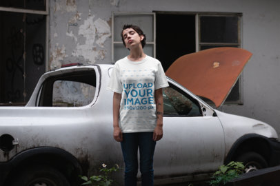 Mockup of a Woman Wearing a Unisex T-Shirt Against a Rusty Car
