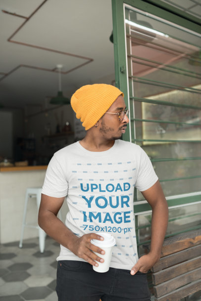 T-Shirt Mockup of a Man Holding a Coffee Cup Outside a Cafe