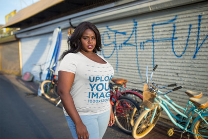 Plus Size T-Shirt Mockup Featuring a Woman Standing in Front of Bicycles 