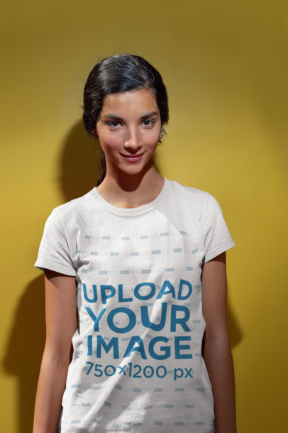 Tshirt Mockup of a Smiling Woman Standing Against a Yellow Wall