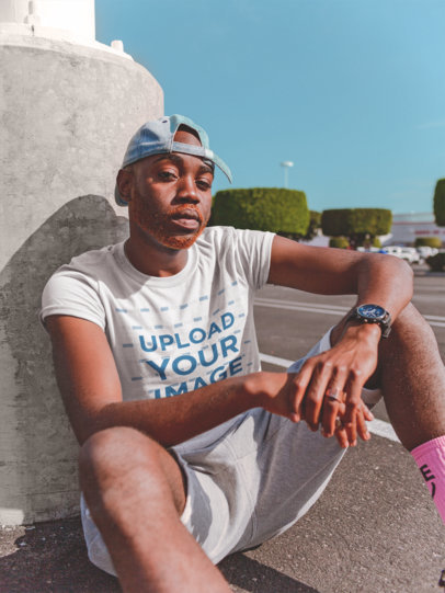 Mockup of a Man Wearing a T-Shirt Sitting in a Parking Lot