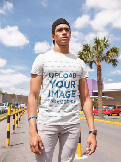 Mockup of a Young Man Wearing a Tshirt by a Palm Tree at a Parking Lot 22412