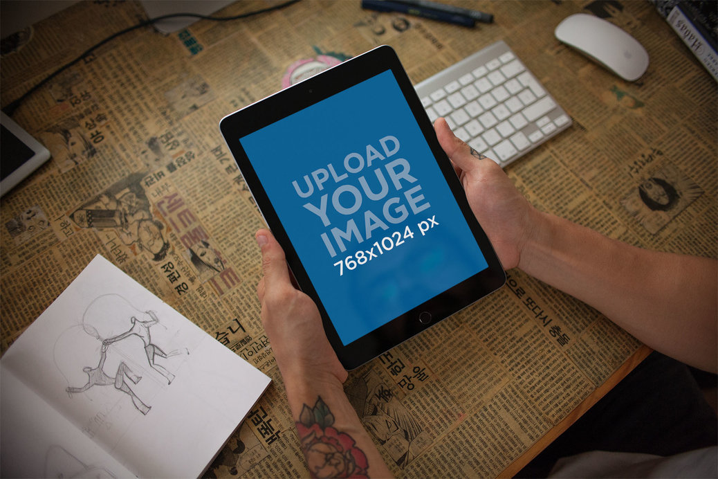 Mockup of an iPad Held by a Man Over his Desk