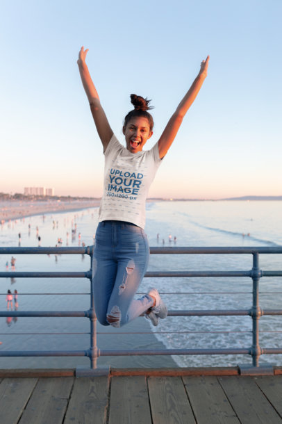 T-Shirt Mockup of a Woman Jumping on a Pier at the Beach