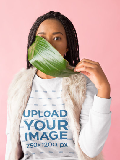 Mockup of a Girl with Braids Wearing a Sweater Holding a Big Leaf Against her Mouth 18374