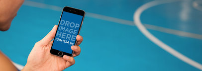 Mockup of a Young Man Using iPhone 6 at a Basketball Court