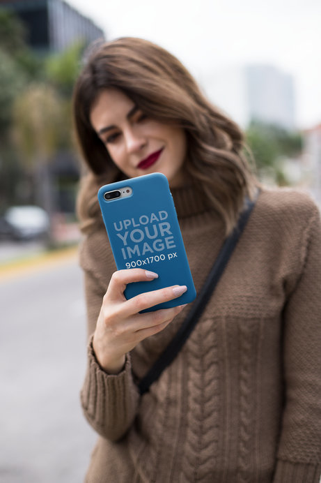 Mockup of an iPhone Case Held by a Pretty Woman Wearing a Sweater