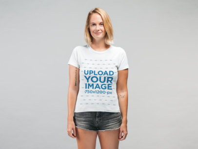 Mockup of a Smiling Woman Wearing a T-Shirt and Denim Shorts at a Studio