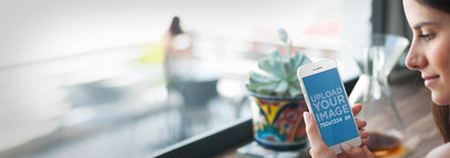 Mockup of Young Woman Using an iPhone 6 at a Local Restaurant