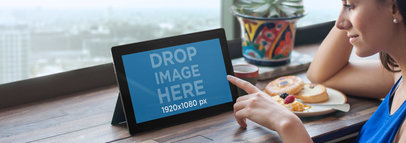 Mockup of a Young Woman Using Windows Tablet at a Restaurant