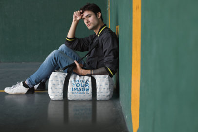 Mockup of a Man Sitting Against a Wall with a Duffel Bag