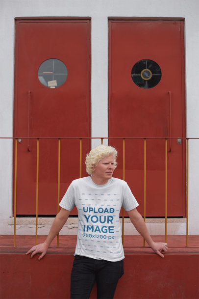 T-Shirt Mockup of a Man Standing in Front of Two Red Doors