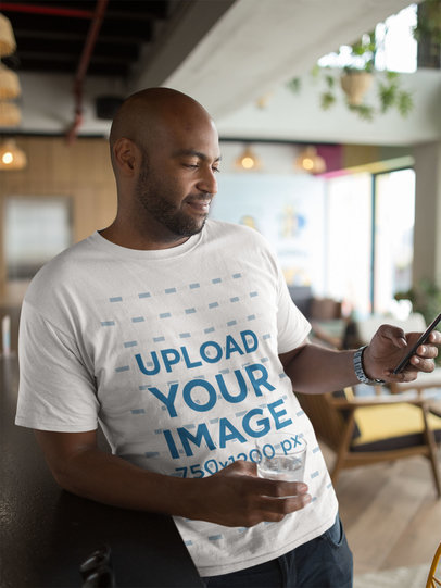 Tshirt Mockup of a Man Using His Phone at a Restaurant