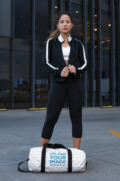 Duffle Bag Mockup Featuring a Sporty Woman Outside a Building