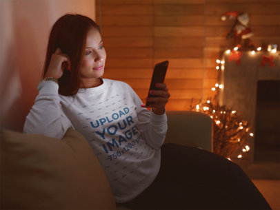 Sweatshirt Mockup of a Woman Using Her Phone On Christmas