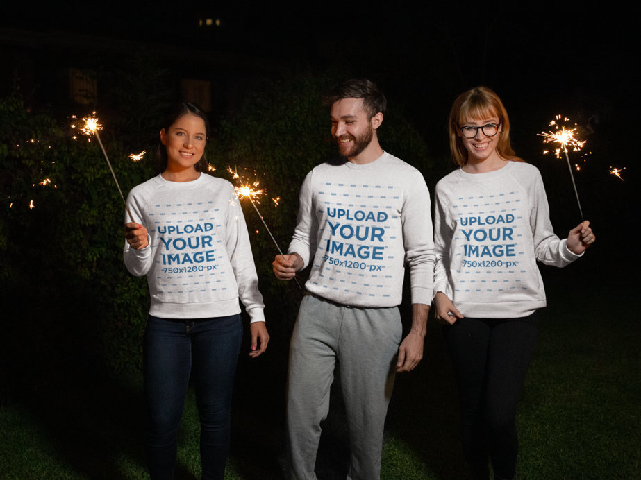 Christmas Sweater Mockup Featuring Three Friends Holding Sparklers