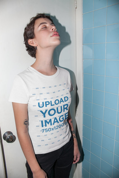 Mockup of a Woman in a Blue Tile Room Wearing a T-Shirt 22200