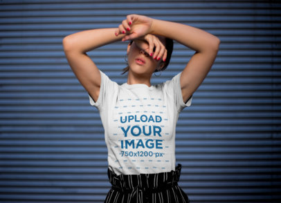 T-Shirt Mockup of a Stylish Woman Posing in Front of a Blue Wall