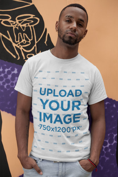 T-Shirt Mockup of a Man Leaning on a Wall with Street Art 