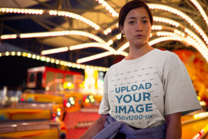 Unisex Tee Mockup Featuring a Serious Woman In Front of a Carnival Ride