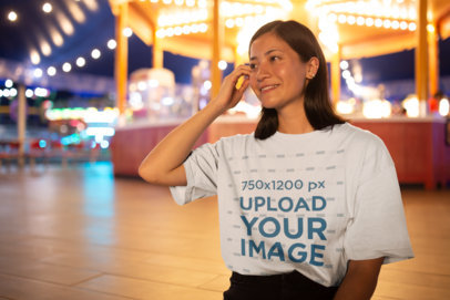 Mockup of a Smiling Woman Wearing a Slouchy Tee by a Carousel