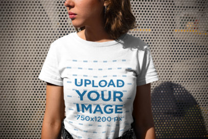 Closeup Mockup of a Woman Wearing a Round Neck Tee Looking to the Left Against Metal Fence 20689
