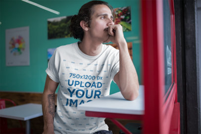 T Shirt Mockup Featuring a Tattooed Man Waiting at a Coffee Shop
