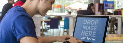 Mockup of a Young Man Working on his Macbook Pro at a Restaurant